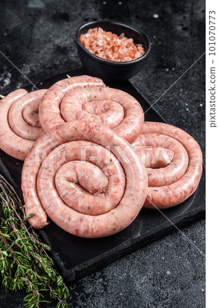 Traditional Raw spiral sausages on a marble board with thyme. Black background. Top view 101070773
