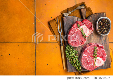 Osso buco Veal shank, raw cross cut veal shank, Italian Ossobuco. Orange background. Top view. Copy space 101070896