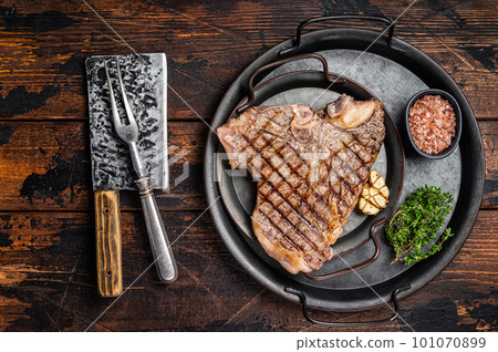 BBQ Grilled T-bone or Porterhouse beef meat Steak on a steel tray with herbs. Wooden background. Top view BBQ Grilled T-bone or Porterhouse beef meat Steak on a steel tray with herbs. Wooden background. Top view 101070899