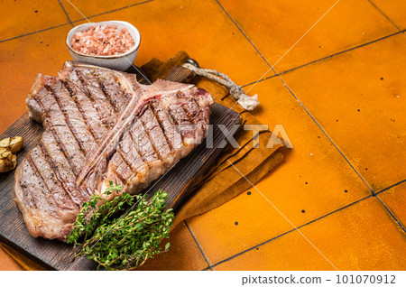 BBQ Roast T bone or Porterhouse beef meat Steak on a wooden board with spices. Orange background. Top view. Copy space 101070912