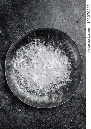 Menthol Crystals in a steel small plate. Black background. Top view 101070925