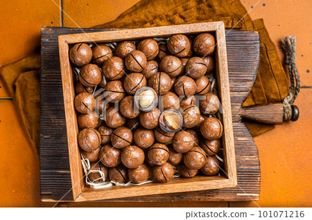 Macadamia natural nuts in a box. Orange background. Top view Macadamia natural nuts in a box. Orange background. Top view 101071216