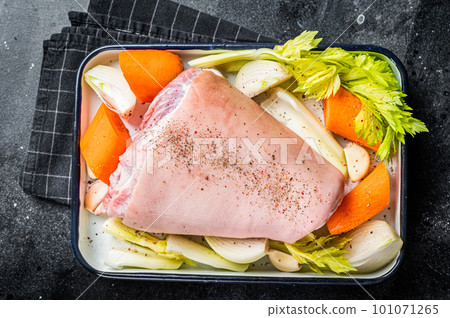 Cooking of Schweinshaxe from Raw pork shank knuckle with vegetables and herbs. Black background. Top view Cooking of Schweinshaxe from Raw pork shank knuckle with vegetables and herbs. Black background. Top view 101071265