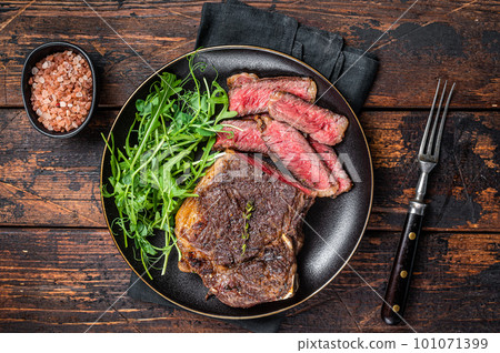 BBQ Grilled Wagyu New York beef meat steak or Striploin steak in a plate with salad. Wooden background. Top view BBQ Grilled Wagyu New York beef meat steak or Striploin steak in a plate with salad. Wooden background. Top view 101071399