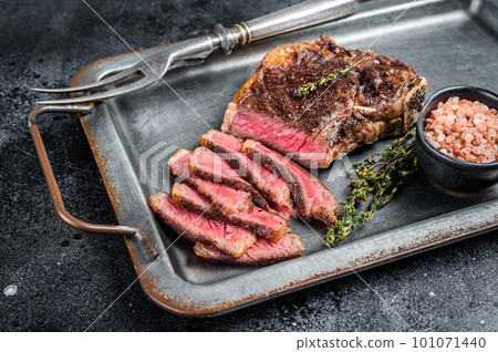 Grilled Wagyu Striploin beef meat steak or new york steak in a steel tray. Black background. Top view 101071440