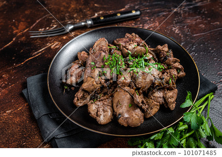 Fried chicken liver with onions and parsley in a plate. Dark background. Top view Fried chicken liver with onions and parsley in a plate. Dark background. Top view 101071485