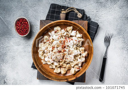 Manti Dumpling with yoghurt and tomato sauce in a wooden plate. White background. Top view 101071745