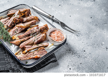 BBQ smoked lamb ribs, mutton spareribs, sliced meat in steel tray with herbs. Gray background. Top view. Copy space 101071817