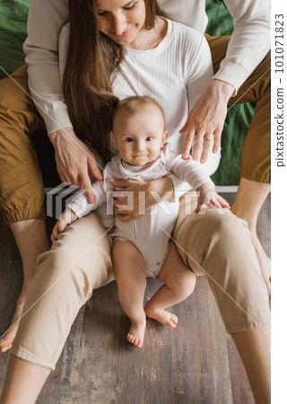 Portrait of a six-month-old baby boy who is hugged by his parents' hands 101071823