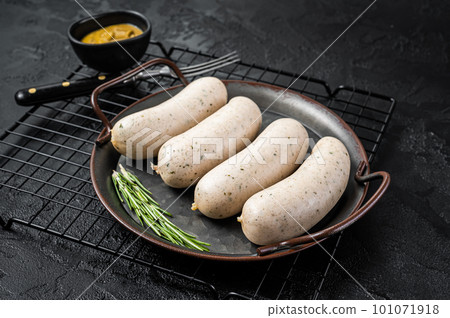 Traditional German Bavarian white sausage in steel tray with mustard. Black background. Top view Traditional German Bavarian white sausage in steel tray with mustard. Black background. Top view 101071918