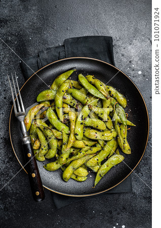 Stir-fried green Edamame Soy Beans with sea salt and sesame seeds in a plate. Black background. Top view Stir-fried green Edamame Soy Beans with sea salt and sesame seeds in a plate. Black background. Top view 101071924