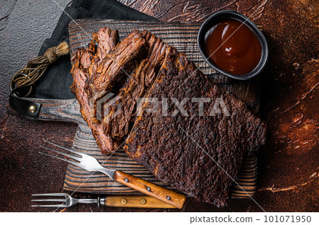 Traditional smoked barbecue wagyu beef brisket on wooden board. Dark background. Top view Traditional smoked barbecue wagyu beef brisket on wooden board. Dark background. Top view 101071950