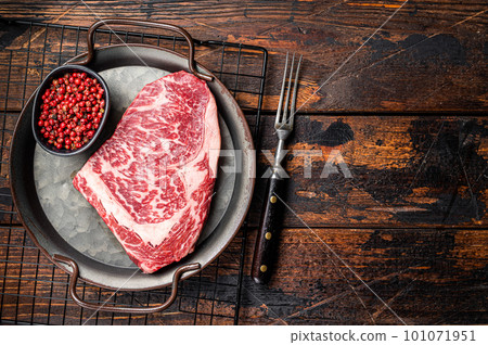 Raw wagyu rib eye beef meat steak in steel tray. Wooden background. Top view. Copy space Raw wagyu rib eye beef meat steak in steel tray. Wooden background. Top view. Copy space 101071951