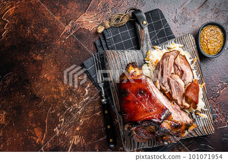 Schweinshaxe Roasted Pork Ham Hock, knuckle with Sauerkraut served on a wooden board. Dark background. Top view. Copy space 101071954