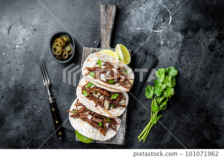 Pork carnitas tacos on corn tortillas with onion and lime. Black background. Top view Pork carnitas tacos on corn tortillas with onion and lime. Black background. Top view 101071962