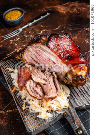 Schweinshaxe Roasted Pork Ham Hock, knuckle with Sauerkraut served on a wooden board. Dark background. Top view 101071966