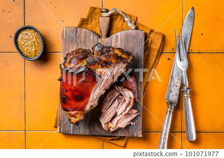 Roasted pork Shank, knuckle on a wooden board. Orange background. Top view 101071977