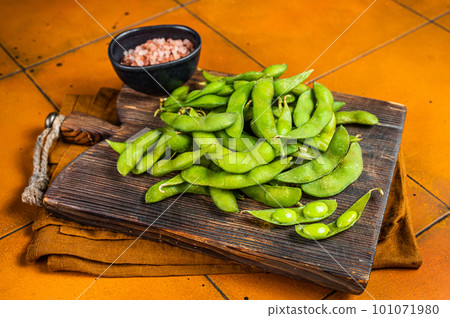 Organic Green Edamame Beans, raw soy beans on wooden board. Orange background. Top view Organic Green Edamame Beans, raw soy beans on wooden board. Orange background. Top view 101071980