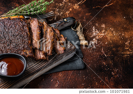 Traditional smoked barbecue wagyu beef brisket on wooden board. Dark background. Top view. Copy space 101071981