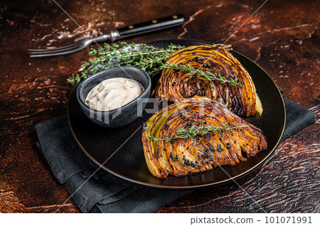 Vegan grilled cabbage steaks with sauce on a black plate. Dark background. Top view Vegan grilled cabbage steaks with sauce on a black plate. Dark background. Top view 101071991