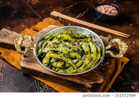 Roasted green Edamame Soy Beans with sea salt and sesame seeds in a skillet. Dark background. Top view Roasted green Edamame Soy Beans with sea salt and sesame seeds in a skillet. Dark background. Top view 101072004