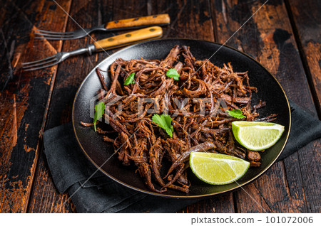 Carnitas in a plate with celery and lime wedges. Wooden background. Top view Carnitas in a plate with celery and lime wedges. Wooden background. Top view 101072006