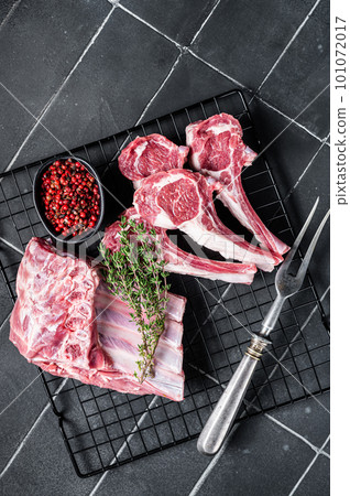 Fresh Raw lamb meat chop steaks on kitchen table with spices and herbs. Black background. Top view 101072017