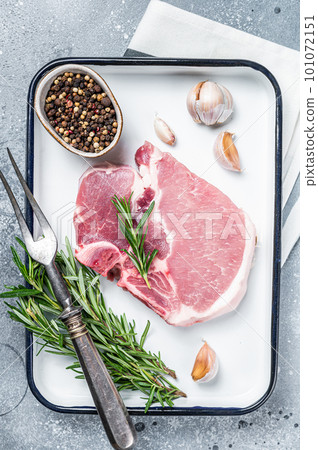 Ready for cooking Raw pork t-bone chop meat steak with herbs and spices. Gray background. Top view Ready for cooking Raw pork t-bone chop meat steak with herbs and spices. Gray background. Top view 101072151