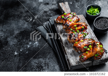 Chicken buffalo wings in sweet and sour sauce with black sesame. Black background. Top view. Copy space 101072162