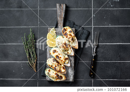 Mussels in Roquefort cheese sauce in shells on wooden board. Black background. Top view 101072166
