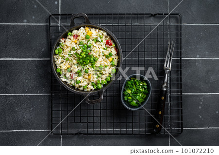 Asian Fried rice with egg and vegetables in a skillet. Black background. Top view 101072210