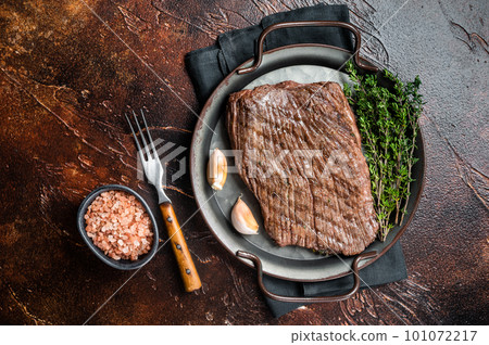 Grilled flank beef steak with herbs. Dark background. Top view Grilled flank beef steak with herbs. Dark background. Top view 101072217