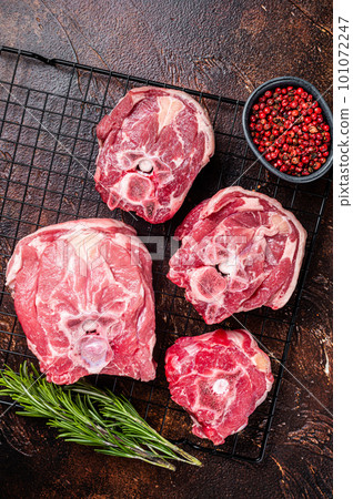 Fresh Raw lamb neck meat slices, mutton meat on a rack with herbs. Dark background. Top view Fresh Raw lamb neck meat slices, mutton meat on a rack with herbs. Dark background. Top view 101072247