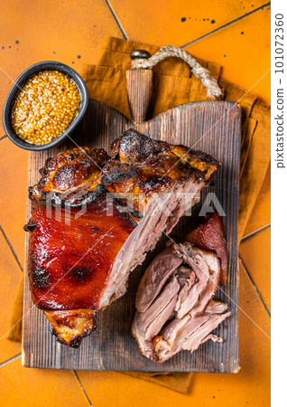 Roasted pork Shank, knuckle on a wooden board. Orange background. Top view 101072360