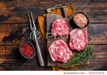 Fresh Raw lamb neck meat with bone on a wooden board with herbs. Wooden background. Top view Fresh Raw lamb neck meat with bone on a wooden board with herbs. Wooden background. Top view 101072418