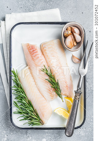 Uncooked Raw cod loin fillet steaks with herbs in kitchen tray. Gray background. Top view 101072452