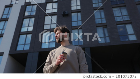 Attractive bearded man holding take away cup with coffee office center on background. Attractive bearded man holding take away cup with coffee office center on background. 101073072