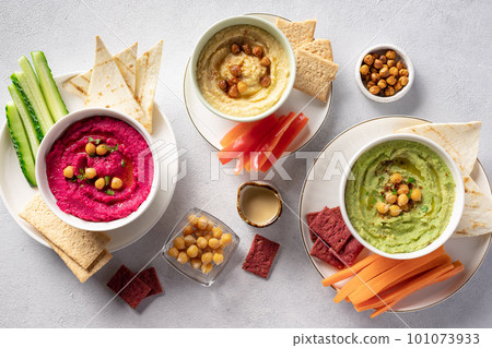 assorted hummus dips in bowls, served with fresh vegetables and crackers. 101073933