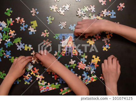 childrens hands collect puzzle on dark table. childrens hands collect puzzle on dark table. 101074125