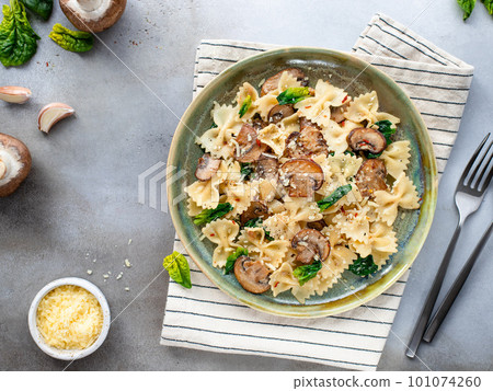 farfalle pasta with spinach and mushrooms in green ceramic plate. 101074260