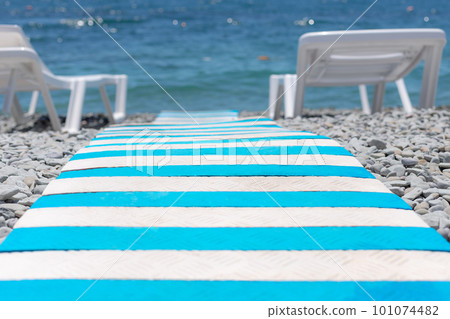 close-up of striped beach path between sun loungers close-up of striped beach path between sun loungers 101074482
