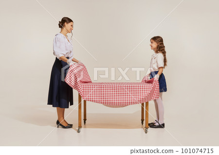 Portrait of charming woman and little girl, mother and daughter set table isolated over light background Portrait of charming woman and little girl, mother and daughter set table isolated over light background 101074715