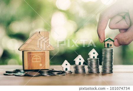 House placed on coins Men's hand is planning savings money of coins to buy a home concept. House placed on coins Men's hand is planning savings money of coins to buy a home concept. 101074734