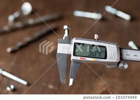 Modern electronic caliper on blurred wooden background Modern electronic caliper on blurred wooden background 101074949