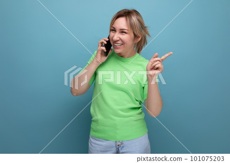 horizontal photo of a cheerful joyful adorable blond woman with a smartphone in her hands on a blue horizontal photo of a cheerful joyful adorable blond woman with a smartphone in her hands on a blue 101075203