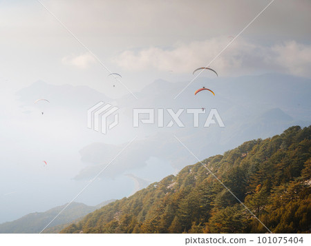 Paragliding in sky. Paraglider tandem flying over sea and mountains Paragliding in sky. Paraglider tandem flying over sea and mountains 101075404