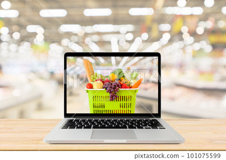 supermarket aisle blurred background with laptop computer and shopping basket on wood table grocery online concept 101075599