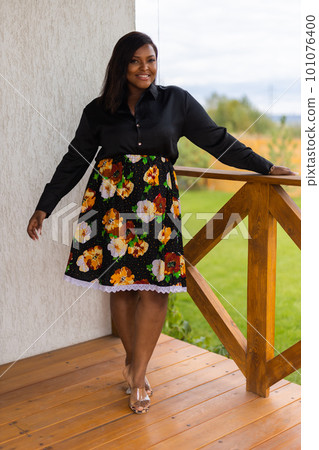 African american woman relaxing and enjoying sun while standing at terrace or balcony at sunlight at summer. Slow living and tranquil moment and mental health. Backyard terrace vacation weekend African american woman relaxing and enjoying sun while standing at terrace or balcony at sunlight at summer. Slow living and tranquil moment and mental health. Backyard terrace vacation weekend 101076400