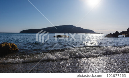 Wild Aegean sea pebble beach, rocks and sun beam Wild Aegean sea pebble beach, rocks and sun beam 101077263