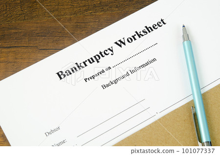 The Someone filling out Bankruptcy worksheet with pen on wooden background. 101077337